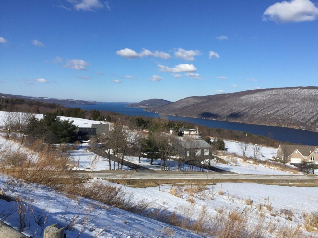 A snowy landscape with a lake and mountains in the background