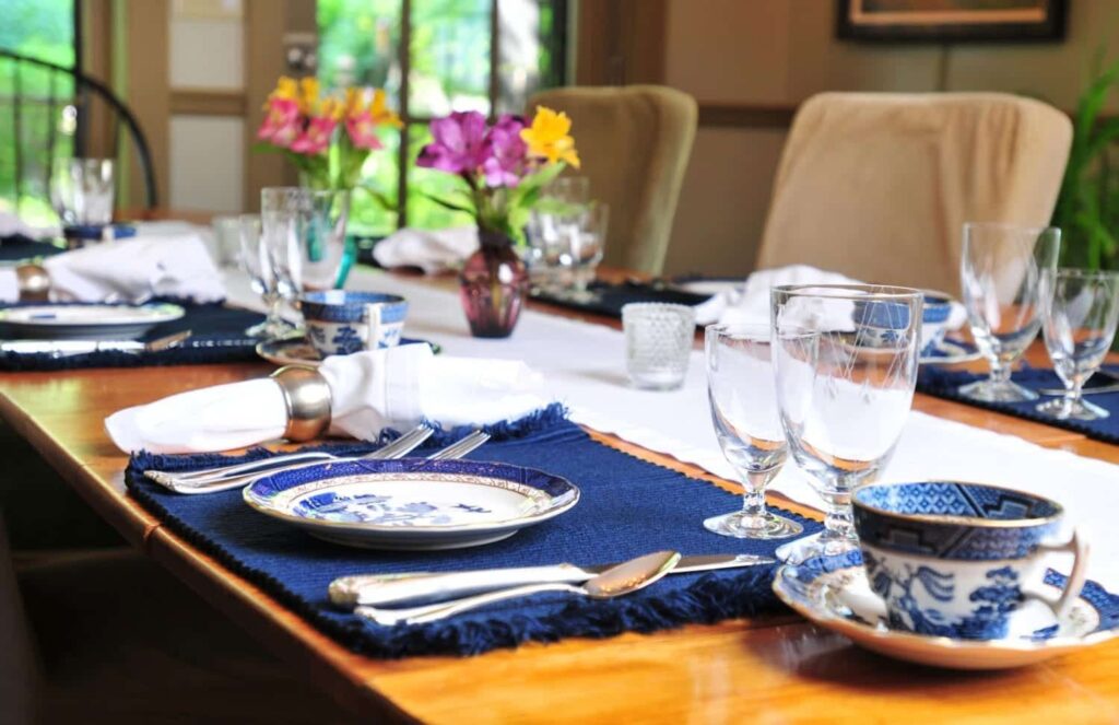 A table set for a meal with plates , cups , glasses and flowers on it.