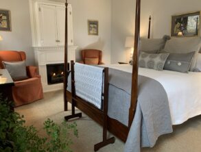 Cozy four poster bed and seating area with fireplace at this Finger Lakes Bed and Breakfast.