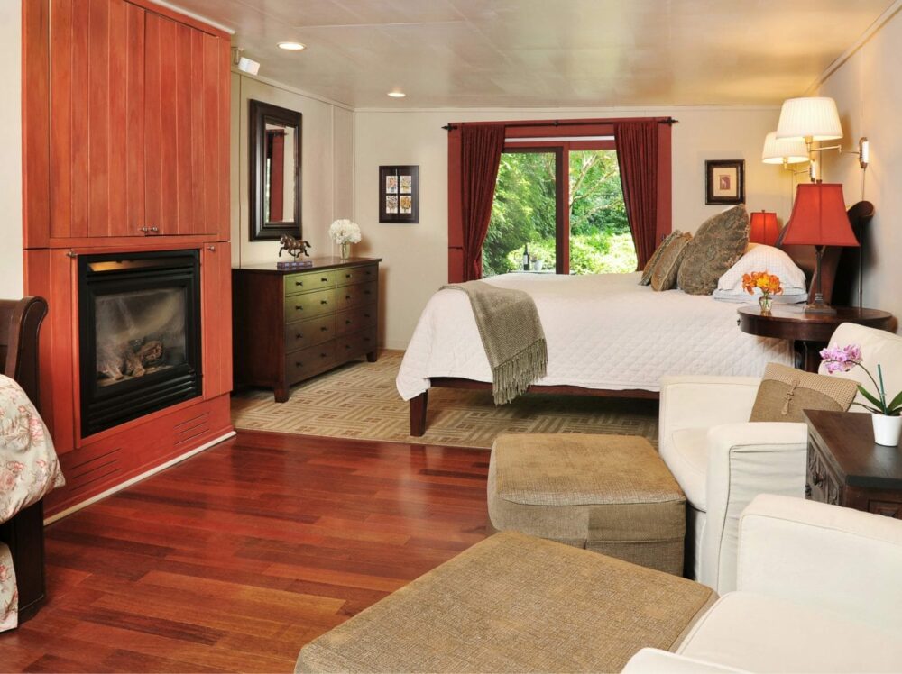 Barn Suite bedroom with bed, blazing fireplace, chairs for relaxing