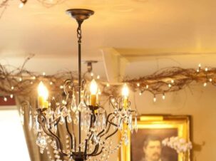The Gathering Room at the 1795 Acorn Inn has a chandelier as it's center. Along two rods that run across the ceiling, grapevine is entwine with small white lights to create a romantic atmostphere.