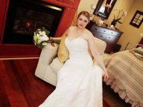 bride in a white strapless wedding gown holding bouquet sitting in chair in front of fireplace in the Barn Suite of the 1795 Acorn Inn Bed and Breakfast... perfect for honeymooners